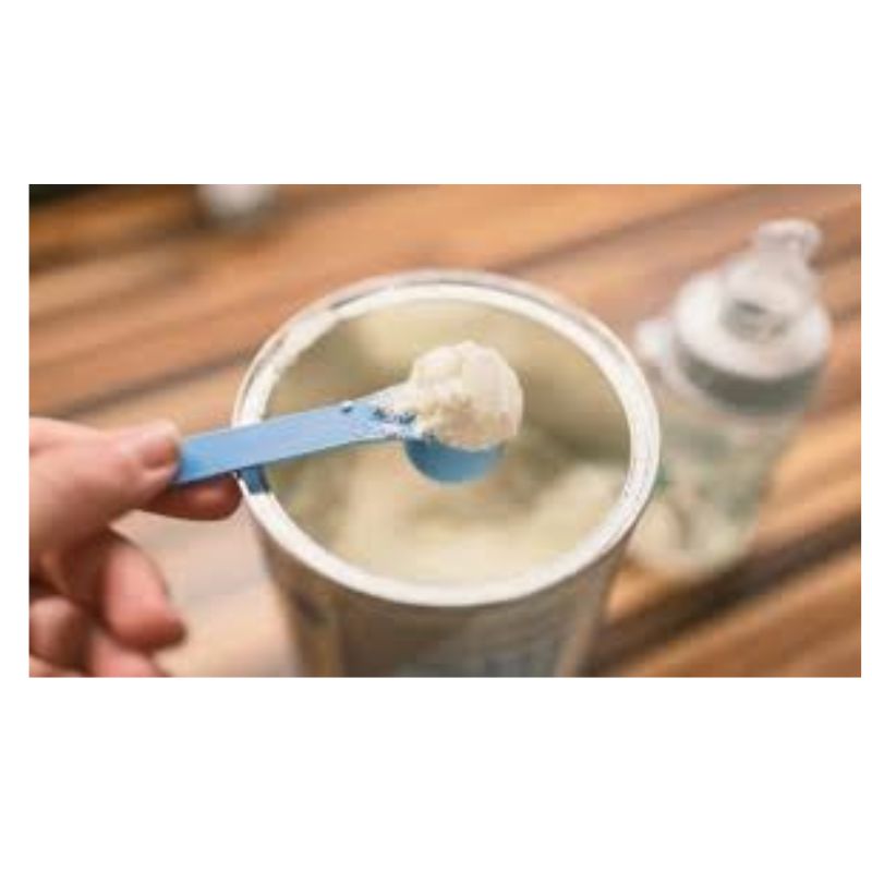 Colher com leite em pó sobre pote de vidro