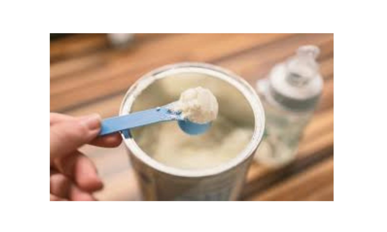 Leite em pó em colher e tigela de vidro sobre a mesa